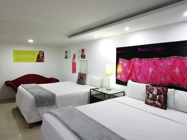 A hotel room with two beds, a small table, a lamp, and a poster on the wall. - All Inclusive MDH (Cancun)