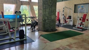 A gym with exercise equipment, a green mat, and a pillar. - All Inclusive MDH (Cancun)