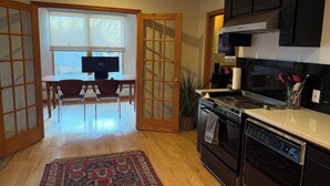 Una cucina dotata di piano cottura, forno, microonde ed elettrodomestici. C'è un'area pranzo con tavolo e sedie, e un'ampia finestra.