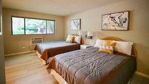 Ein Schlafzimmer mit zwei Betten, großen Fenstern und Bildern an den Wänden.