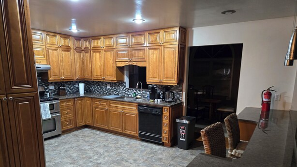 Una cocina con armarios de madera, lavavajillas y extintor.