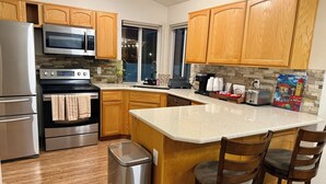 Una cocina moderna con armarios de madera, electrodomésticos de acero inoxidable, una isla grande con taburetes y un salpicadero decorativo.