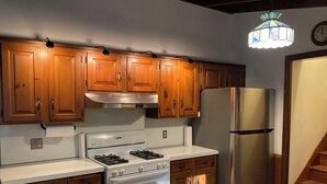 A kitchen with wooden cabinets, a stainless steel refrigerator, a gas stove, and a built-in oven. - Cozy Home in Pownal VT (Pownal)