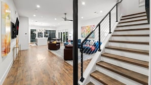 Amplia sala de estar con escalera, piso de madera y muebles modernos.
