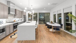 Una cocina moderna con una isla central, electrodomésticos de acero inoxidable y una zona de comedor con una mesa redonda y sillas.