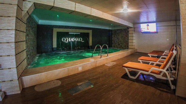 Zona de spa con bañera de hidromasaje, sillas reclinables y televisor montado en la pared.
