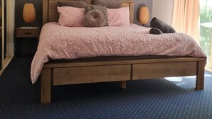 A bedroom with a wooden bed, a ceiling fan, a wall-mounted painting, and a window with curtains. - Splashpark family resort, full of fun. Close to theme parks, beach, restaurants (Mermaid beach)
