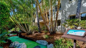 A landscaped outdoor area with palm trees, a green pathway, and a signpost. - Splashpark family resort, full of fun. Close to theme parks, beach, restaurants (Mermaid beach)