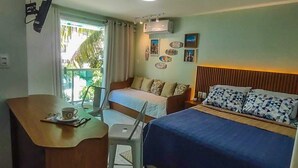 Ett hotellrum med en säng, ett skrivbord med en stol, ett litet bord med en kopp och ett fönster med gardiner.