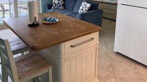 Una cocina compacta con una mesa de madera, un refrigerador blanco y un sofá azul.
