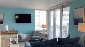 Una sala de estar moderna con un sofá, un televisor, una lámpara y vistas al exterior.