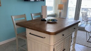 Una cocina con encimera de madera, armarios blancos y un televisor montado en la pared.
