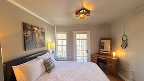 Une chambre à coucher avec un grand lit, une commode, un miroir et un tableau accroché au mur.