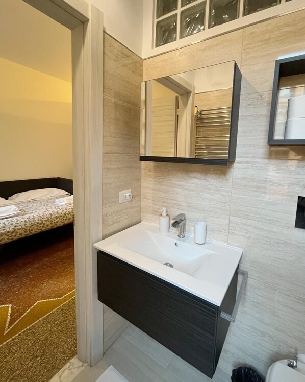 Casa de banho moderna com uma pia grande, espelho e porta-toalhas.