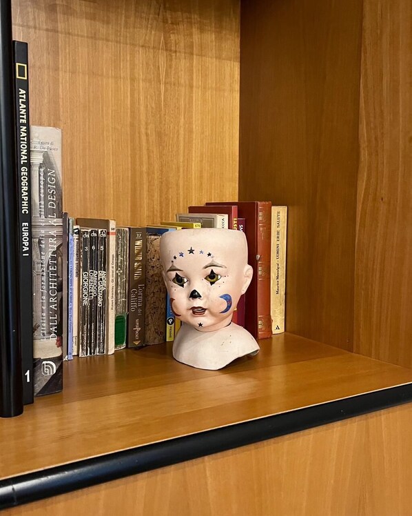 Una estantería de madera con libros y un busto de cerámica.