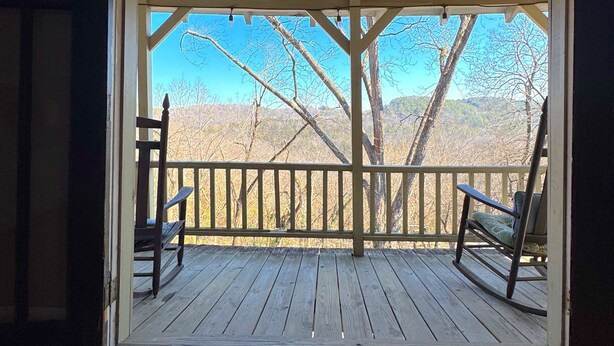 An open wooden deck with two rocking chairs facing a view of leafless trees and a clear sky. - Wishing Star Townhouse on Spring Street (Eureka Springs)
