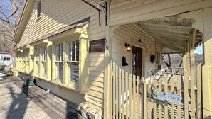 A wooden building with a porch, a sign reading "Welcome," and a small sign above the door. - Wishing Star Townhouse on Spring Street (Eureka Springs)