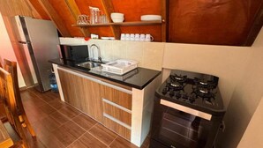 Una cocina funcional con refrigerador, lavamanos, estufa y gabinetes de madera.