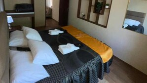 Habitación de hotel con cama, armario, espejo y una alfombra pequeña.