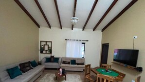 Una sala de estar con sofá, mesa de centro, televisor y mesa de billar.