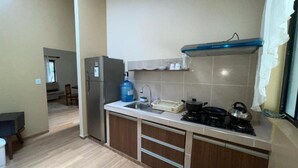 Una cocina compacta con estufa a gas, hervidor y dispensador de agua azul.