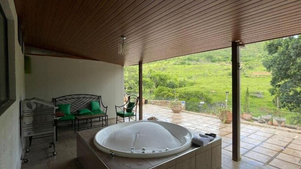 Un área de spa con un jacuzzi, sillas verdes y vistas a un jardín exuberante.