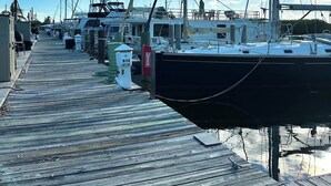 A wooden dock with boats moored on both sides, a clear sky, and a calm water body reflecting the sky. -     Snowbird Paradise Canal-Front 1BR Minutes to Sombrero (Marathon)