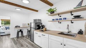 Una cocina moderna con armarios blancos, un refrigerador de acero inoxidable, una encimera de madera y una planta colgante.