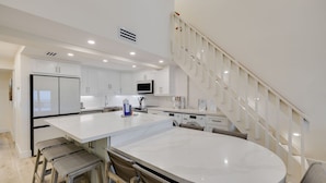 A modern kitchen with white cabinetry, a large island, and a built-in microwave. - Beach Villa 2535- Executive Penthouse Residence on Captiva Island (Captiva)