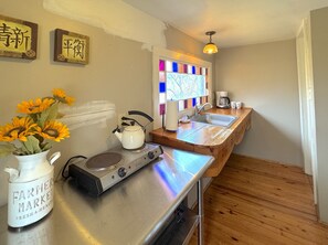 A kitchen with a gas stove, a kettle, a sink, and a vase of sunflowers. - Stepping Stones Townhouse on Spring Street (Eureka Springs)