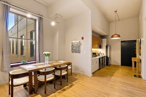 A modern kitchen with wooden cabinets, a countertop, and a hanging pendant light. - The Executive | 2BR | Rooftop Pool + Fireplace (St. Louis)
