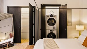 Ein Hotelzimmer mit Bett, Schreibtisch, Stuhl, Waschmaschine und Lampe.