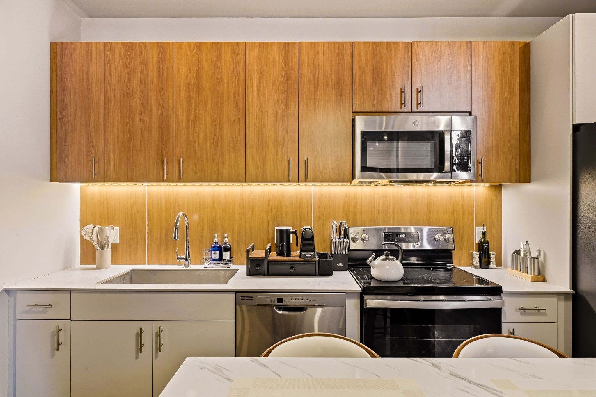 A modern kitchen with wooden cabinets, stainless steel appliances, and a marble countertop.