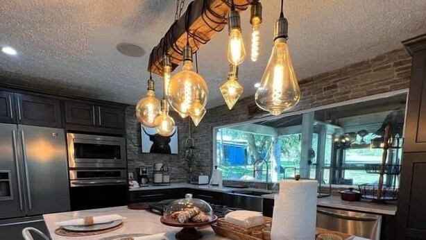 A modern kitchen with a marble countertop, stainless steel appliances, and a unique light fixture. - 10 acres property great for outside activities its great place to make memories (Walton)