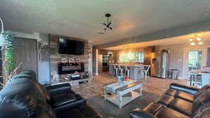 A modern living room with a fireplace, leather sofas, a coffee table, and a TV mounted on the wall. - 10 acres property great for outside activities its great place to make memories (Walton)