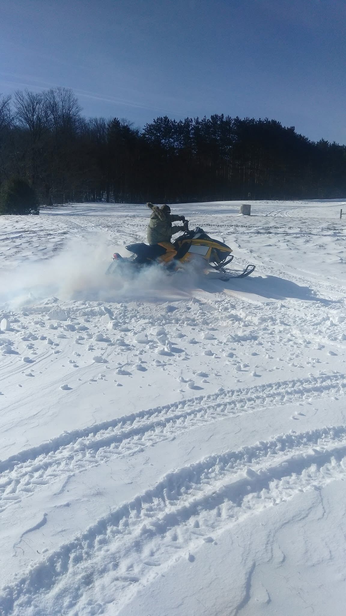 Een sneeuwscooter op een besneeuwd veld met sporen.