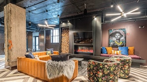 A modern lounge area with a fireplace, seating, and a large mural.