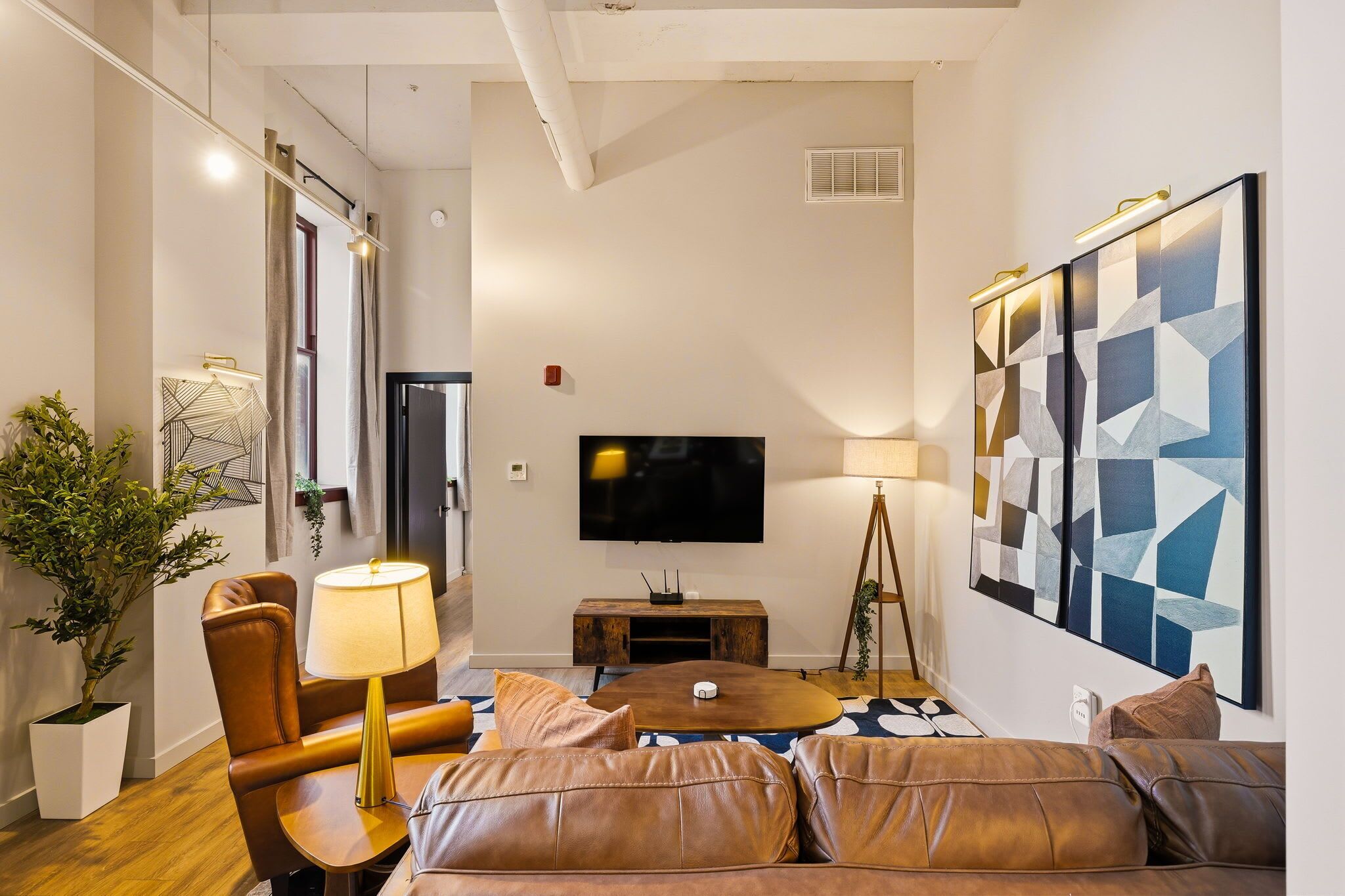 A modern living room with a sofa, a coffee table, a TV, and a painting on the wall.