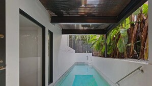 Ein schmales Hallenbad mit einer Glaswand auf der einen Seite und einem Metallgeländer auf der anderen.