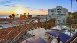 Eine Dachterrasse mit Sonnenuntergangsblick, einem Pool und einem Gebäude im Hintergrund.