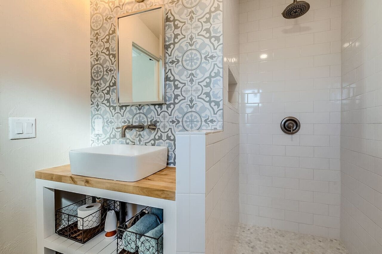 A bathroom with a white sink, a mirror, and a shower.