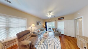 A spacious living room with a large sofa, a patterned rug, and a ceiling fan. - Champions Unit 3707 (Sunset Beach)