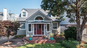 A two-story house with a red front door, a small porch, and a mailbox.