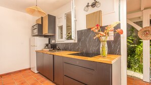 Une cuisine moderne avec des meubles de couleur sombre, un plan de travail en bois et une grande fenêtre.