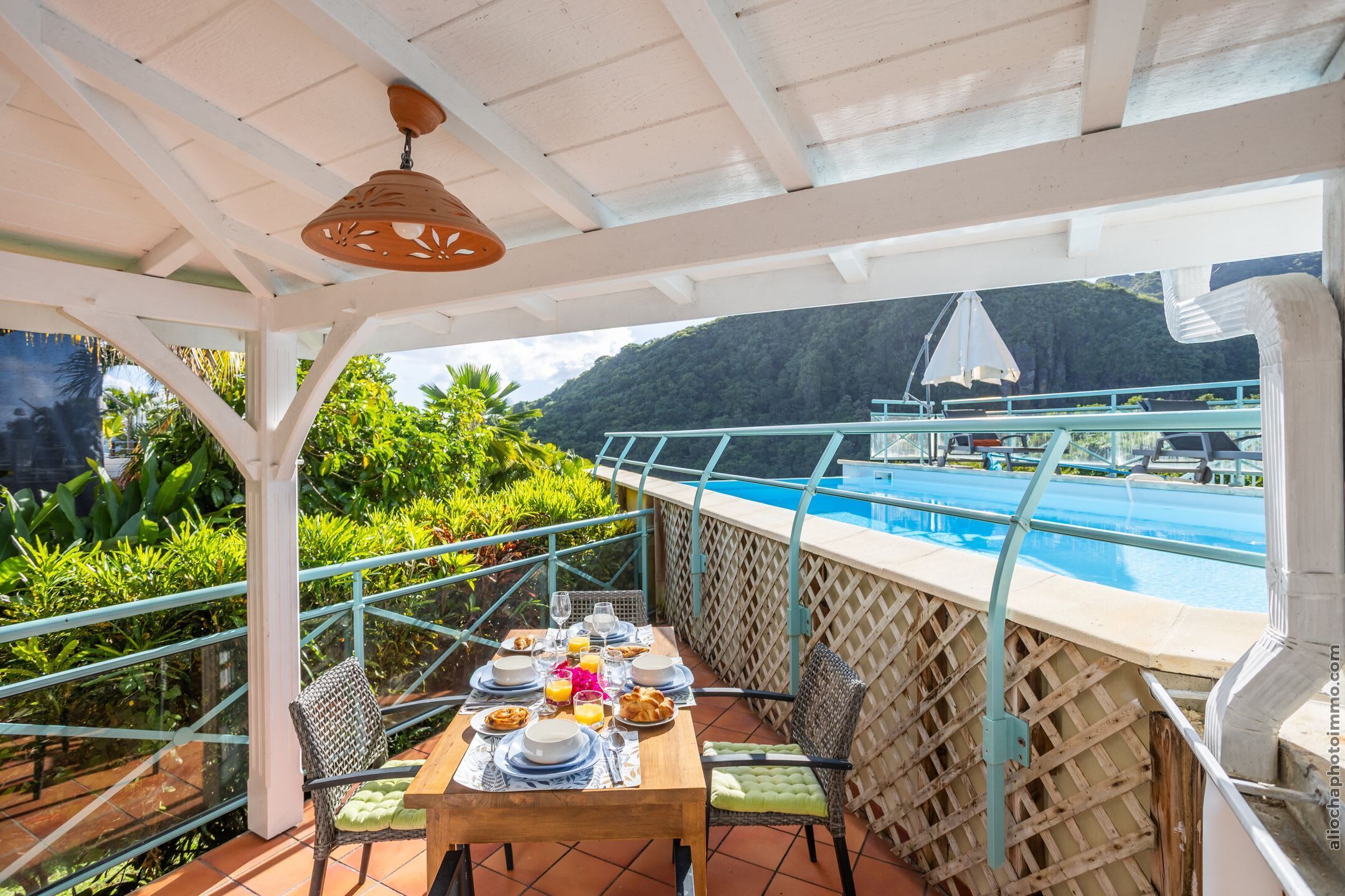 Une terrasse avec vue sur la piscine, un espace repas extérieur aménagé et une végétation luxuriante.