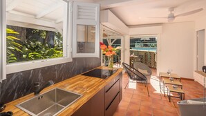 Una cocina moderna con encimera de madera, un lavabo integrado y ventana con vistas a la vegetación.