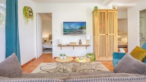Una sala de estar con un sofá, una mesa de centro, un televisor, un mueble de madera y un cuadro en la pared.