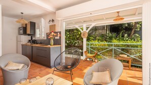 Una cocina moderna con comedor, un amplio ventanal corredera que da a un balcón con plantas.