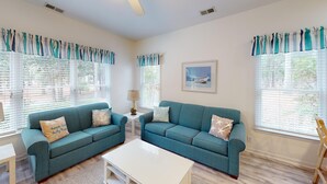 A living room with two teal sofas, a white coffee table, and a painting on the wall. - Club Villas Unit 17D - Lower Level (Sunset Beach)