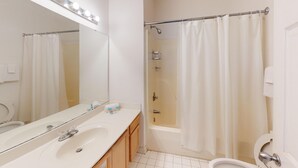 A bathroom with a white sink, mirror, and a shower with a curtain. - Club Villas Unit 17D - Lower Level (Sunset Beach)